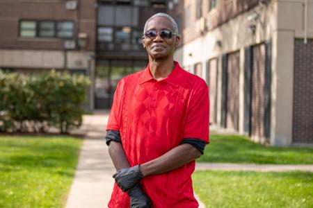 A man wearing a red shirt standing outside a CHA Public Housing building.